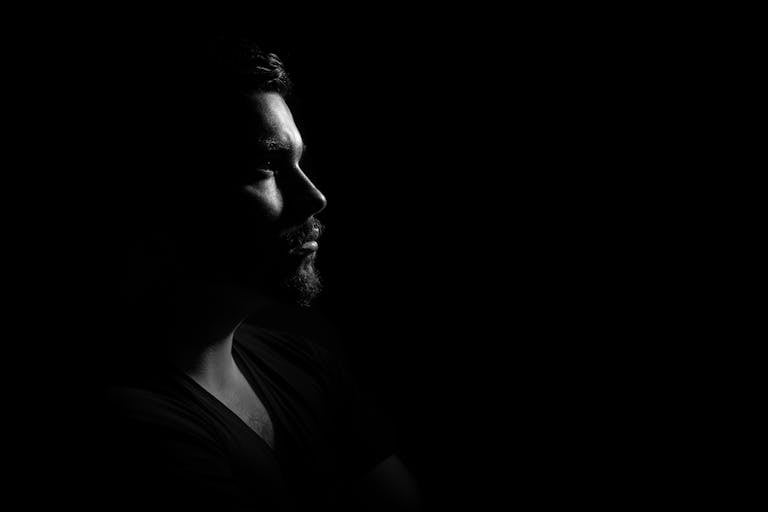 Profile portrait of a man in black and white, emphasizing shadows and highlights.